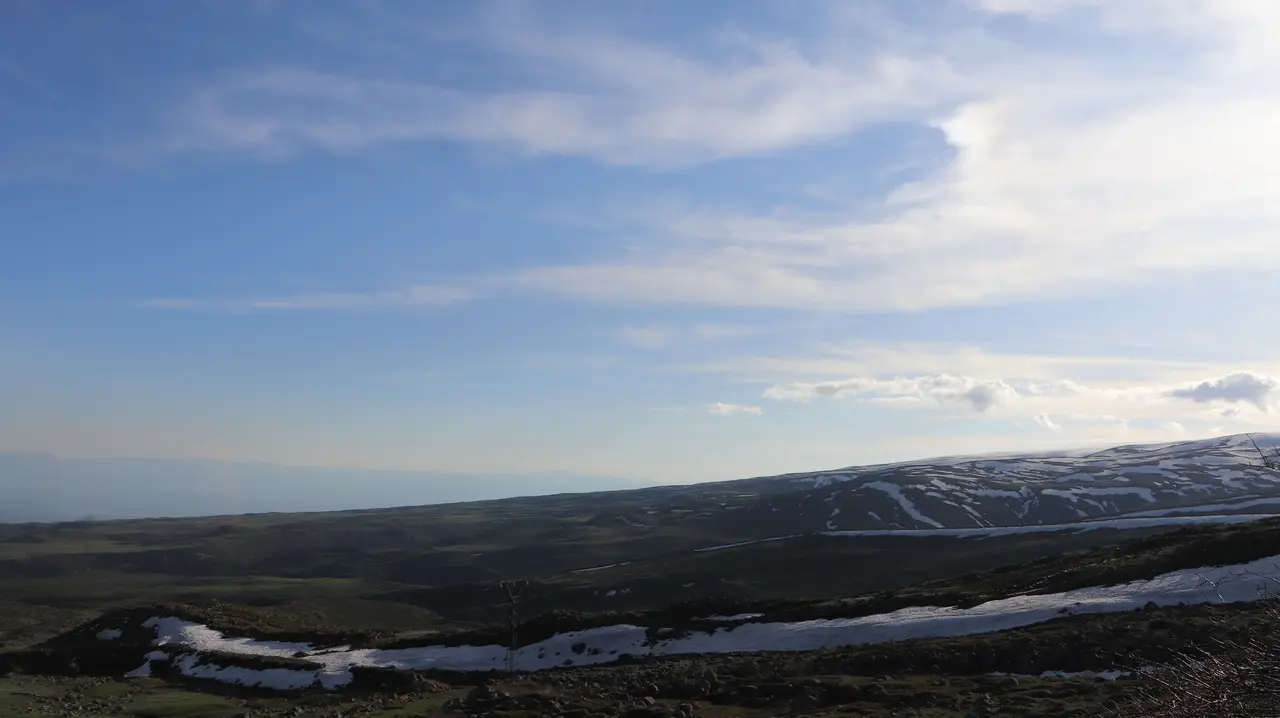 The broad snow-streaked slopes of Mount Aragats rising under a blue sky