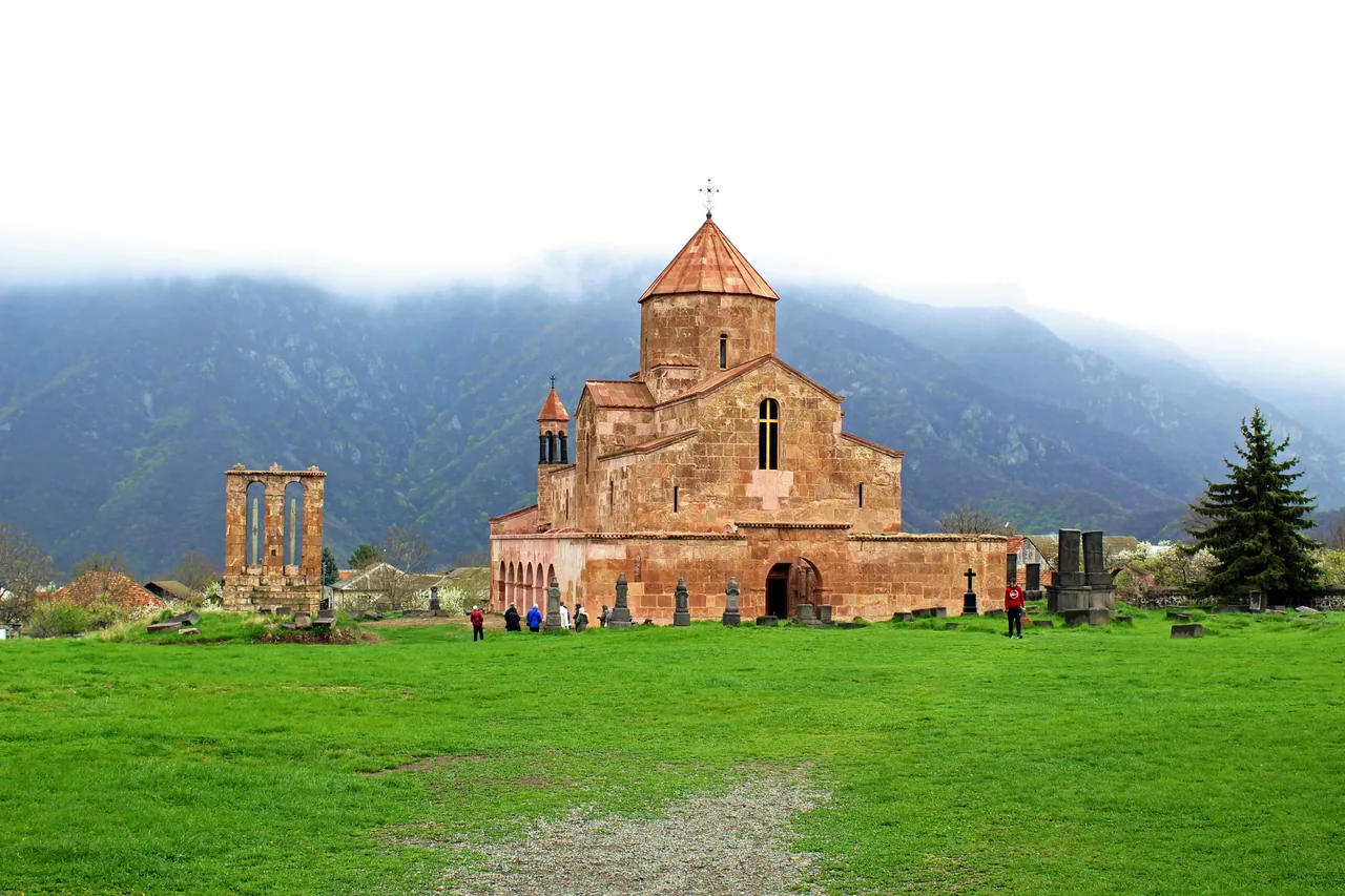 The pink stone basilica of Odzun church standing alone on a green plateau in Lori province