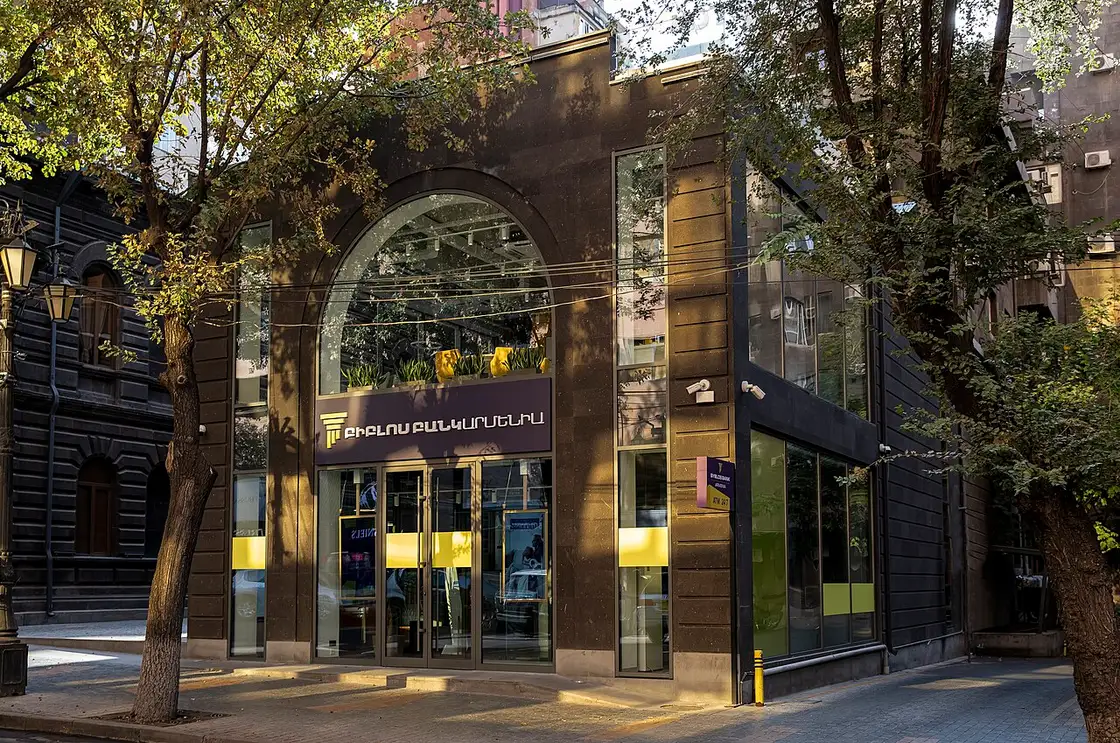 A modern bank branch building in Yerevan with a glass and stone facade on a clear day