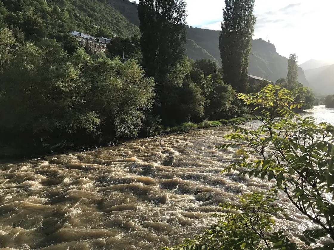 The Debed river running high past houses and wooded hills at Alaverdi in summer