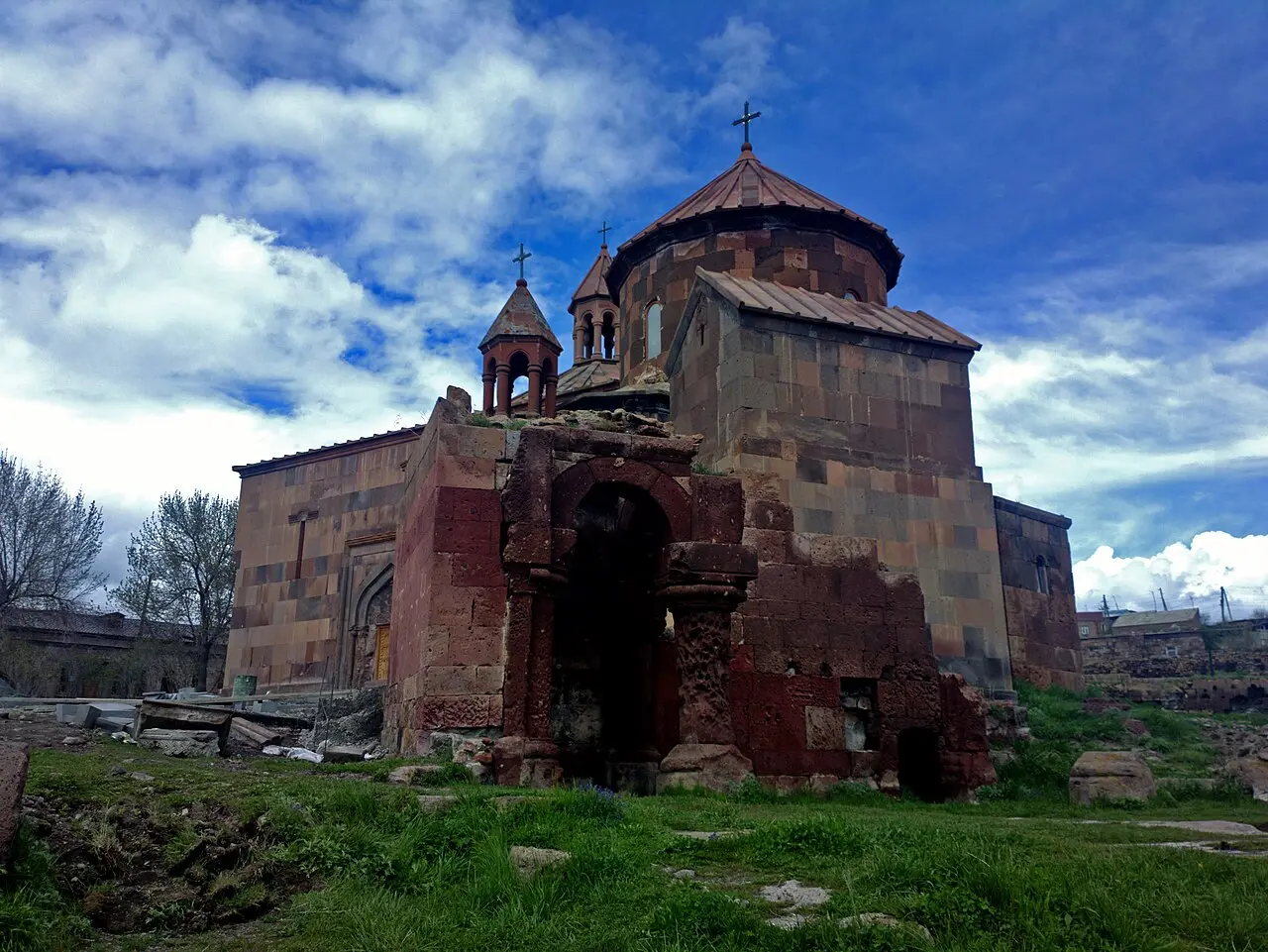 Harichavank monastery in warm brown stone under a dramatic sky, its domed church and gavit near the village of Harich