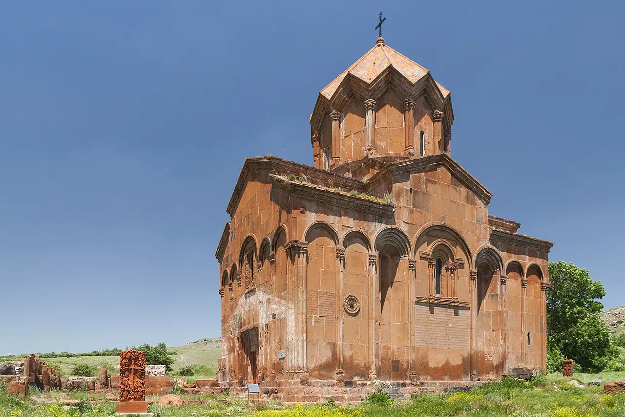 The two surviving churches of Marmashen monastery in red tuff surrounded by trees on the green Shirak plain