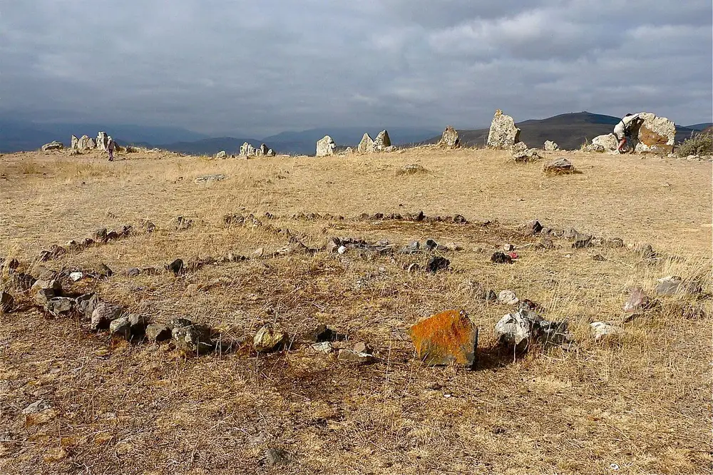 Upright basalt stones and a ring of low stones on the windswept Karahunj plateau near Sisian under a cloudy sky