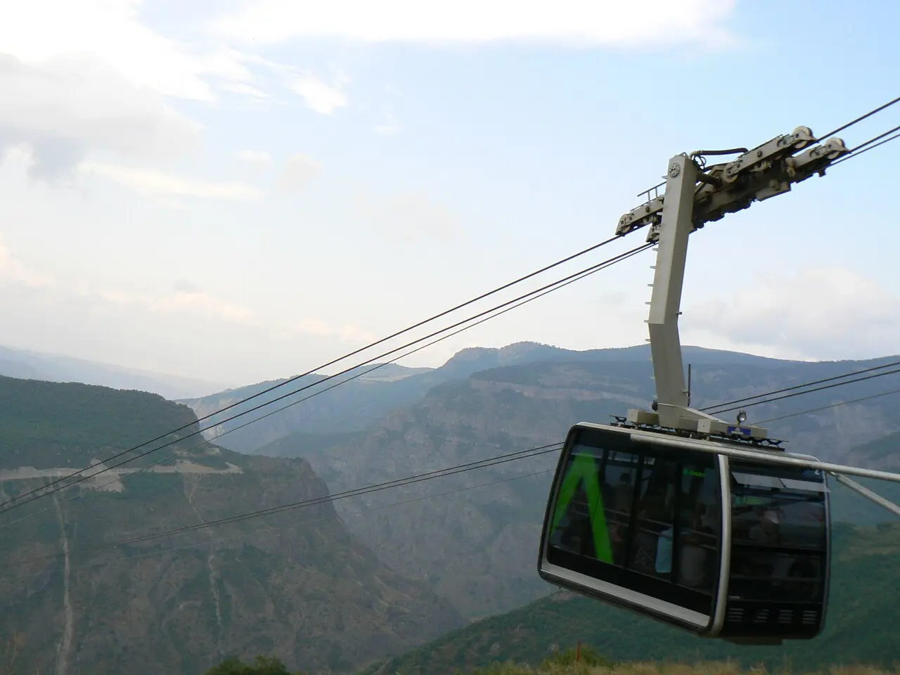 A yellow Wings of Tatev cable-car cabin gliding on its wire high above the wooded Vorotan gorge between Halidzor and Tatev