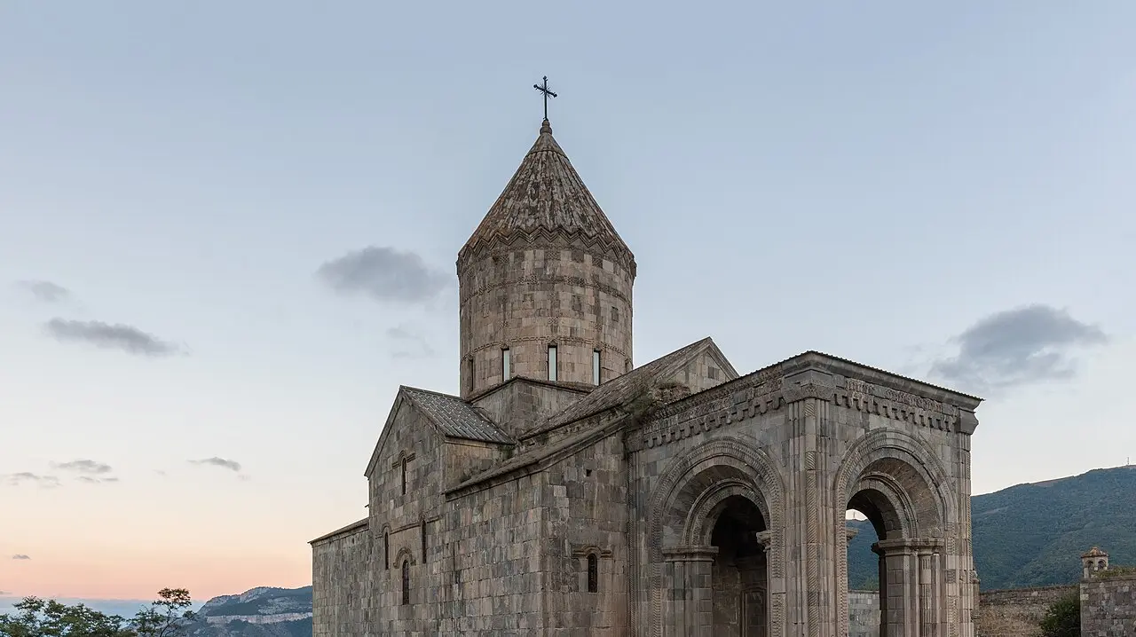 The stone churches and fortified walls of Tatev monastery standing on a green plateau at the edge of the deep Vorotan gorge in southern Armenia
