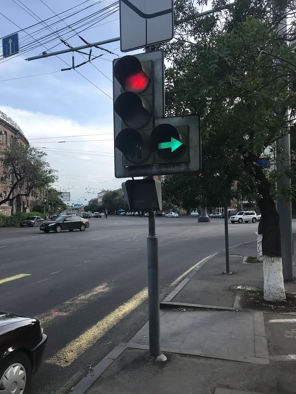 A busy Yerevan intersection with cars, a traffic light and trolleybus wires overhead