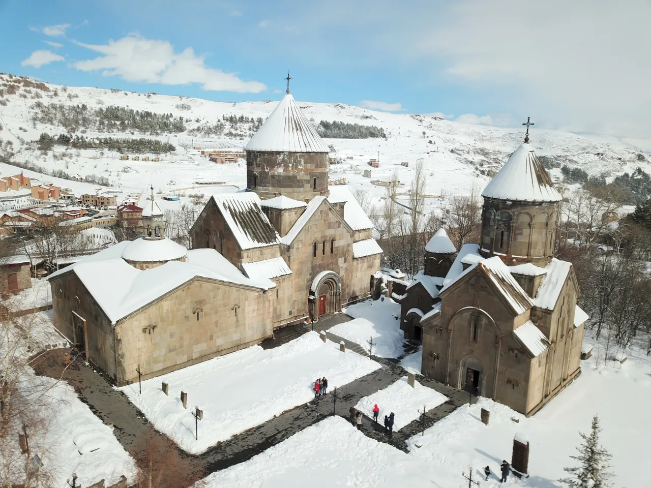 An aerial view of the snow-covered churches of Kecharis Monastery with the Tsaghkadzor valley and snowy hills behind