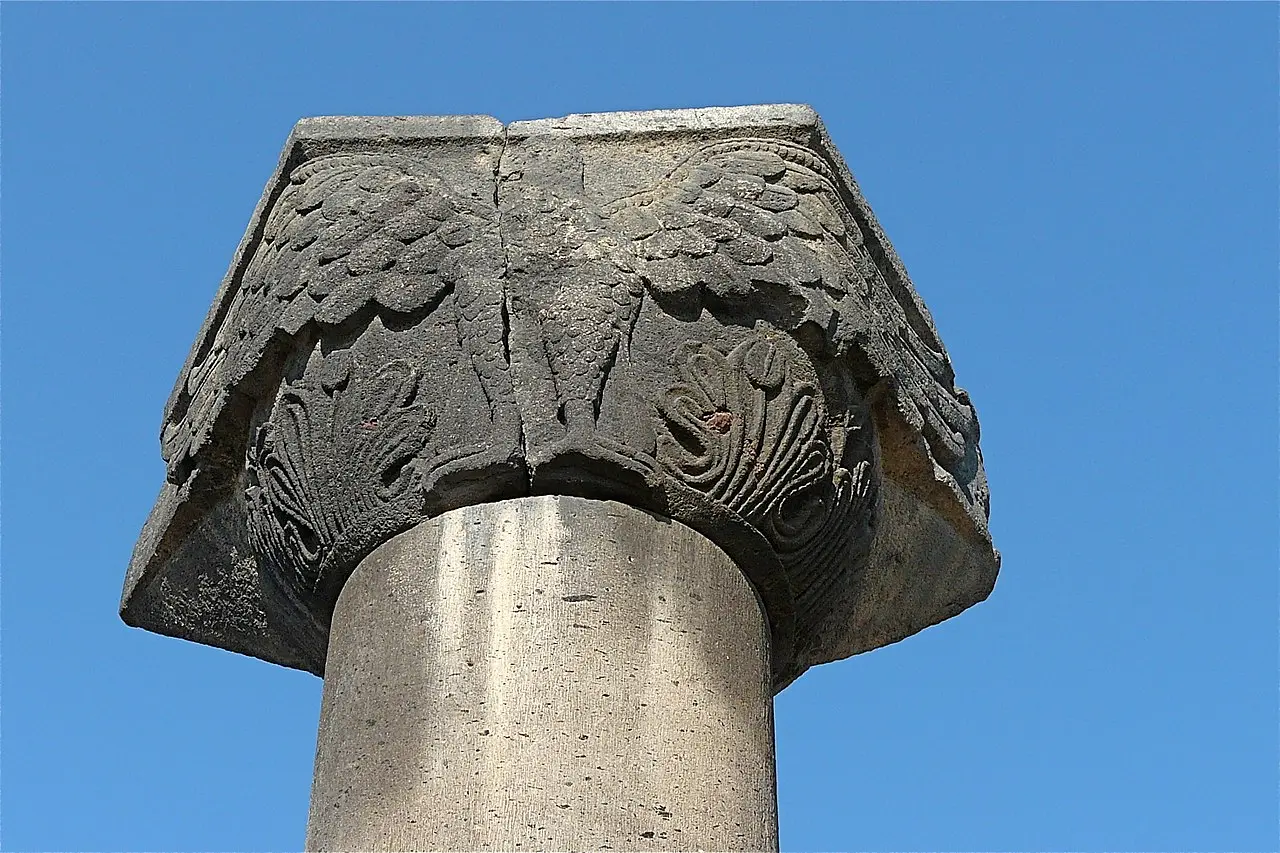 A single carved column standing among the circular stone foundations of the ruined Zvartnots cathedral