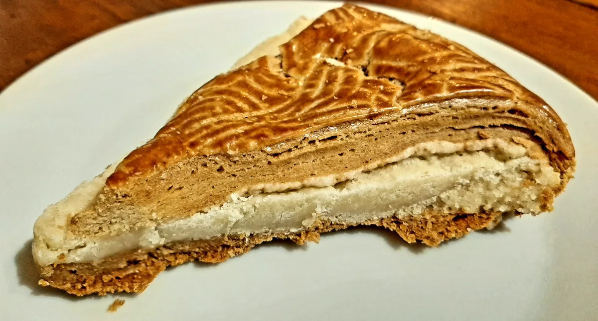 A slice of Armenian gata pastry on a plate, showing its stamped golden crust and buttery filling