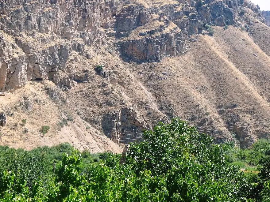 The wide valley at Areni with vineyards and orchards below bare red-brown cliffs