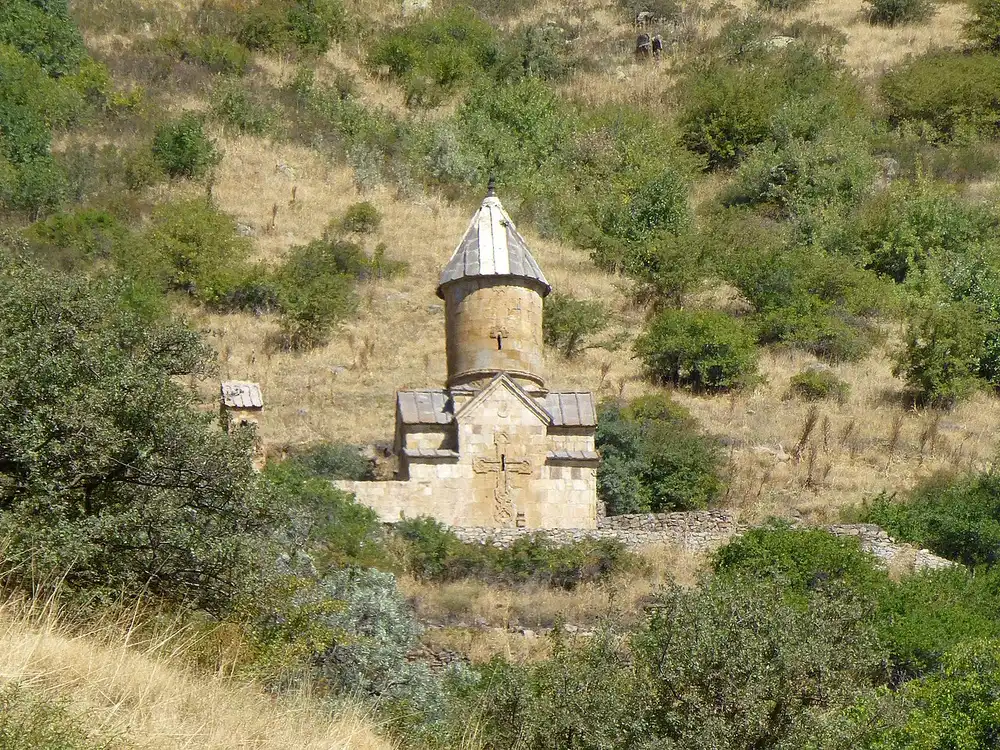 The pale stone walls and belfry of Spitakavor monastery in a green upland valley