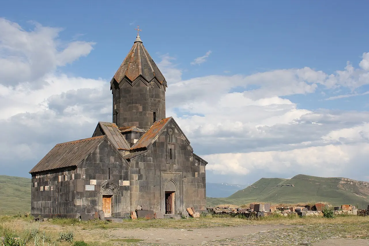 The dark stone church of Tanahat monastery standing alone on a green slope above Vernashen