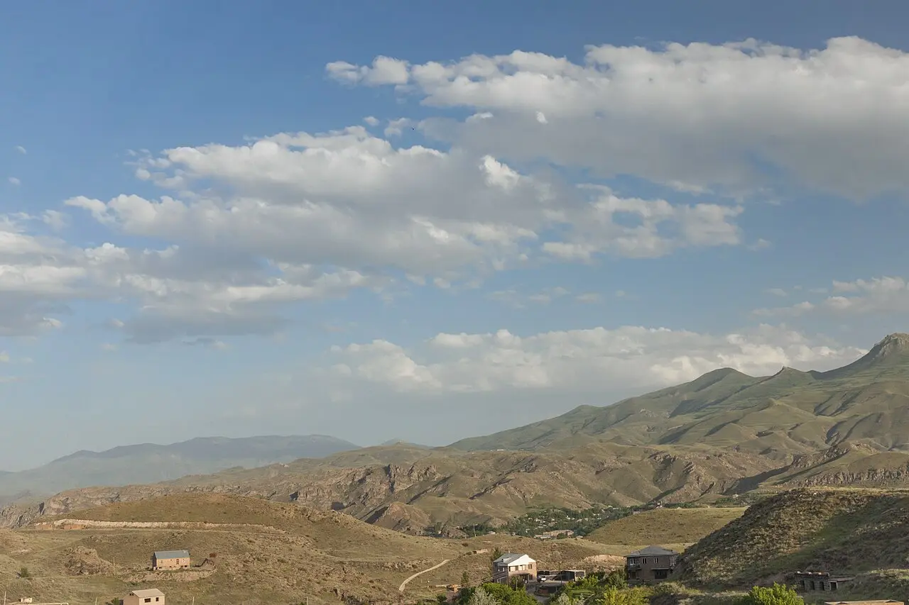 Bare brown ridges and scattered houses in the valley around Yeghegnadzor under a cloudy sky
