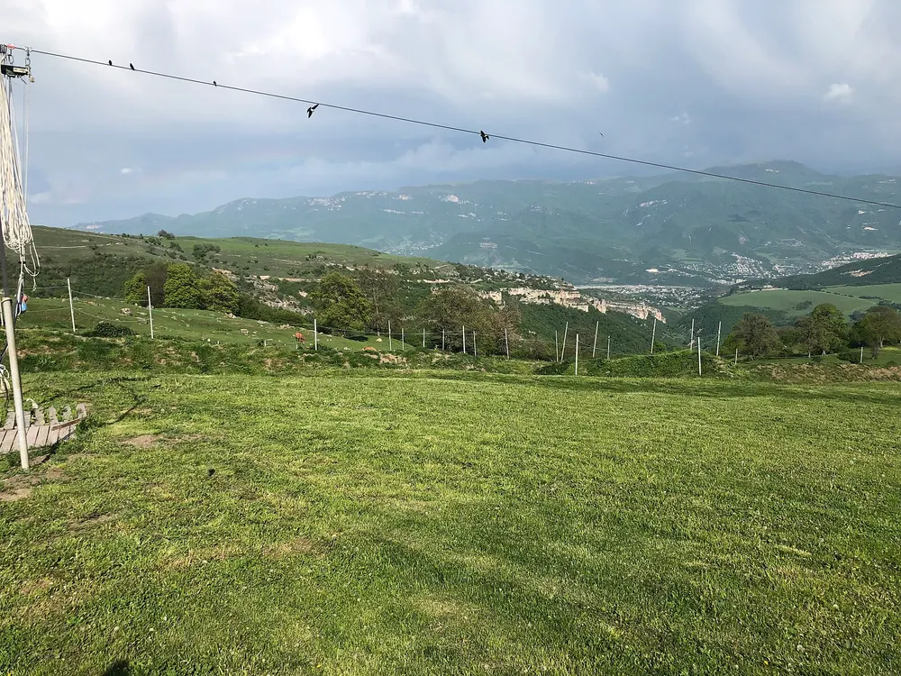 The grassy launch field at Yell Extreme Park with cable poles and the Ijevan valley and cliffs beyond