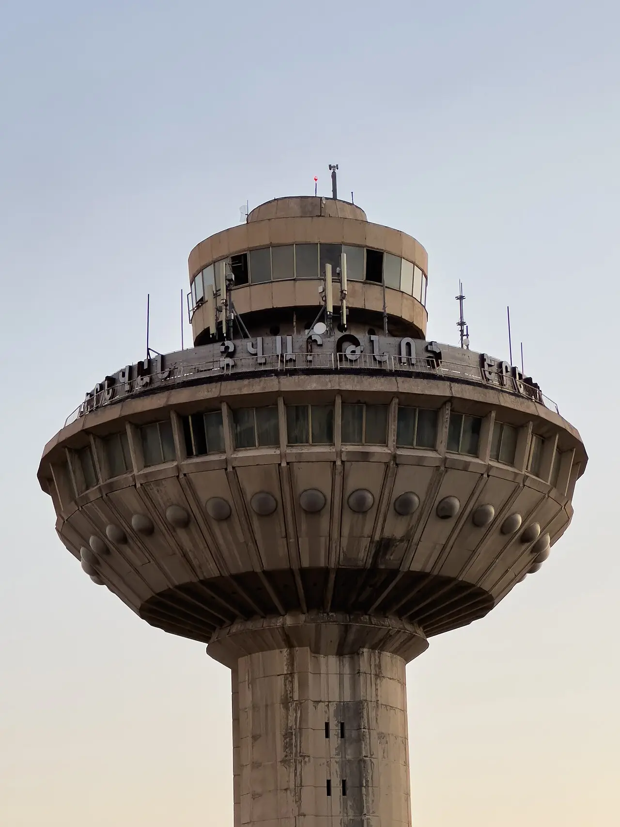The UFO-shaped concrete control tower of the old Soviet-era Zvartnots terminal against a pale evening sky