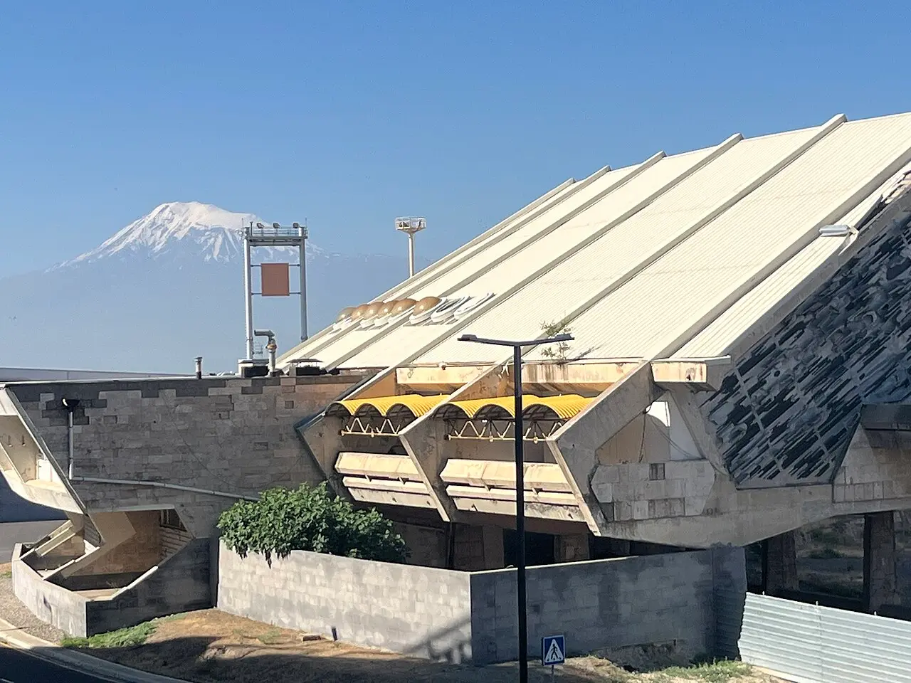 The low ridged roof of the older Zvartnots terminal building with the snow-capped double peak of Mount Ararat rising behind it
