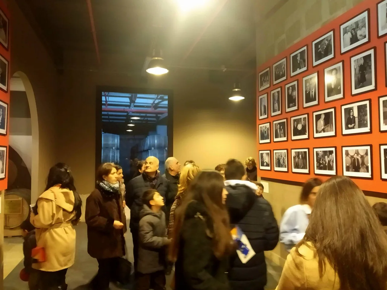 A tour group standing among oak barrels in a stone-walled cellar gallery at the Ararat brandy museum in Yerevan