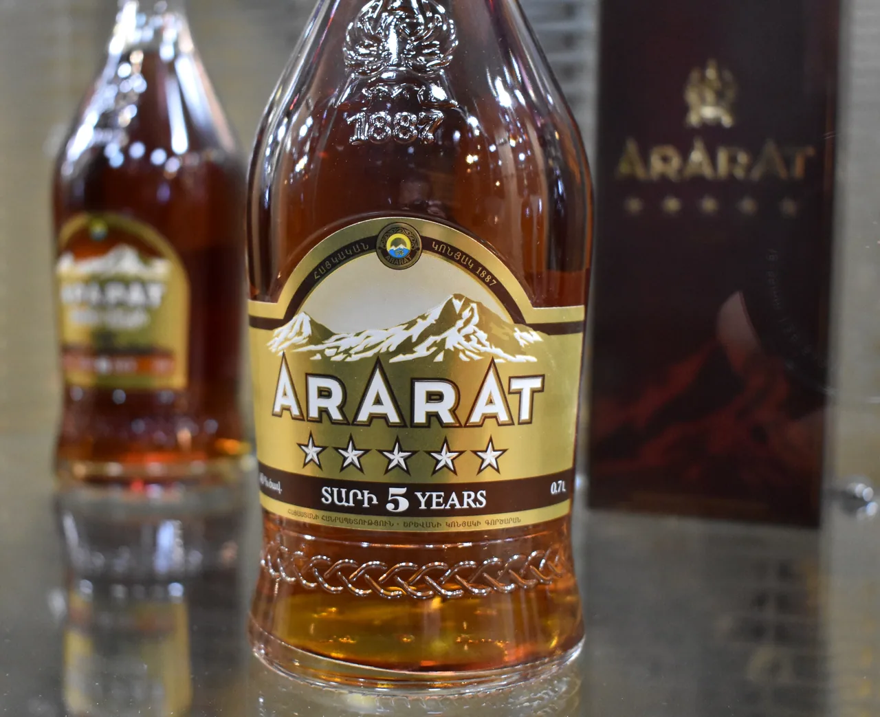 A close-up of an ARARAT five-star brandy bottle showing the mountain label, five stars and 1887 embossed in the glass