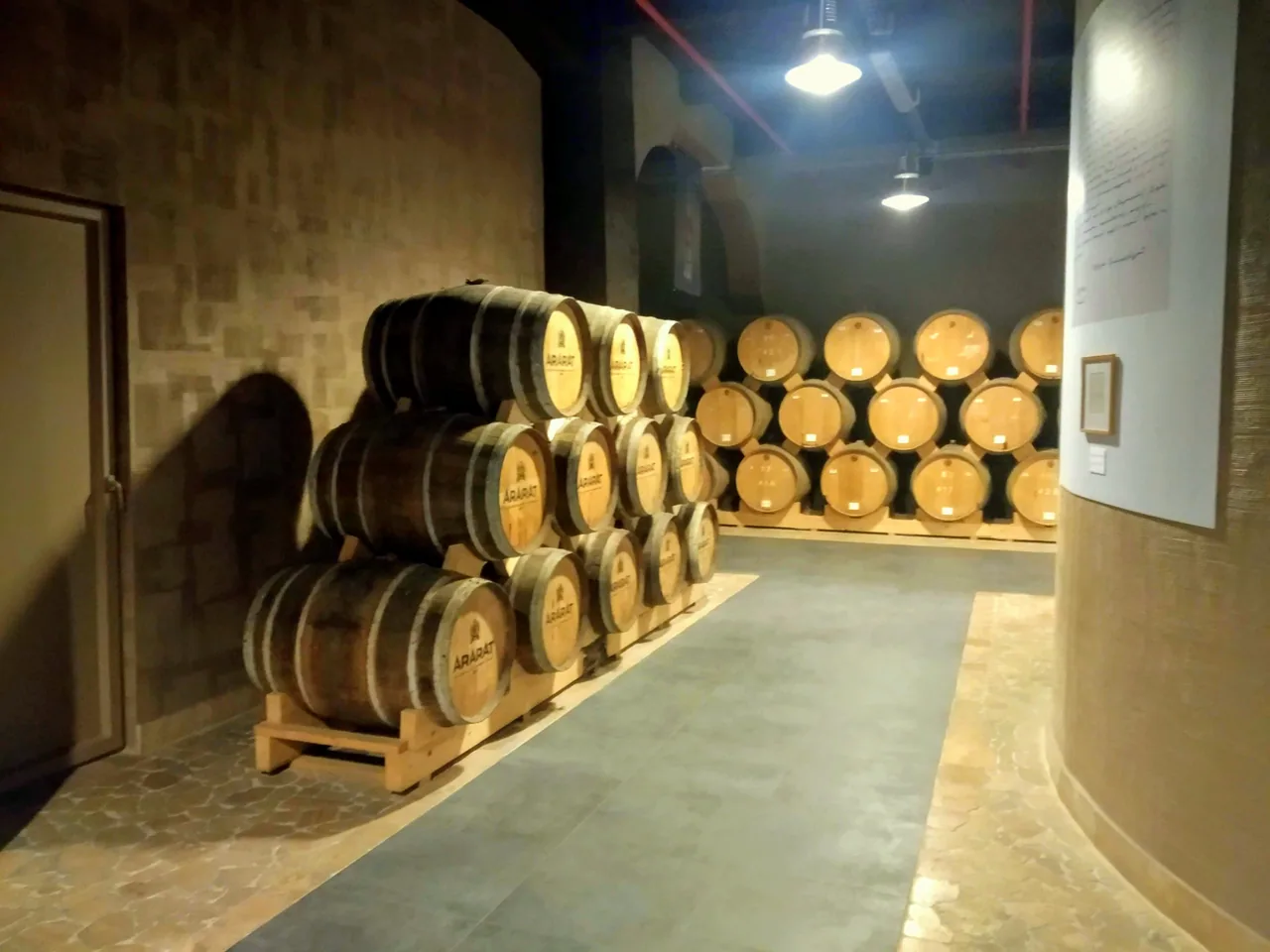 Rows of oak ARARAT barrels stacked in the dim aging cellar of the Yerevan Brandy Company
