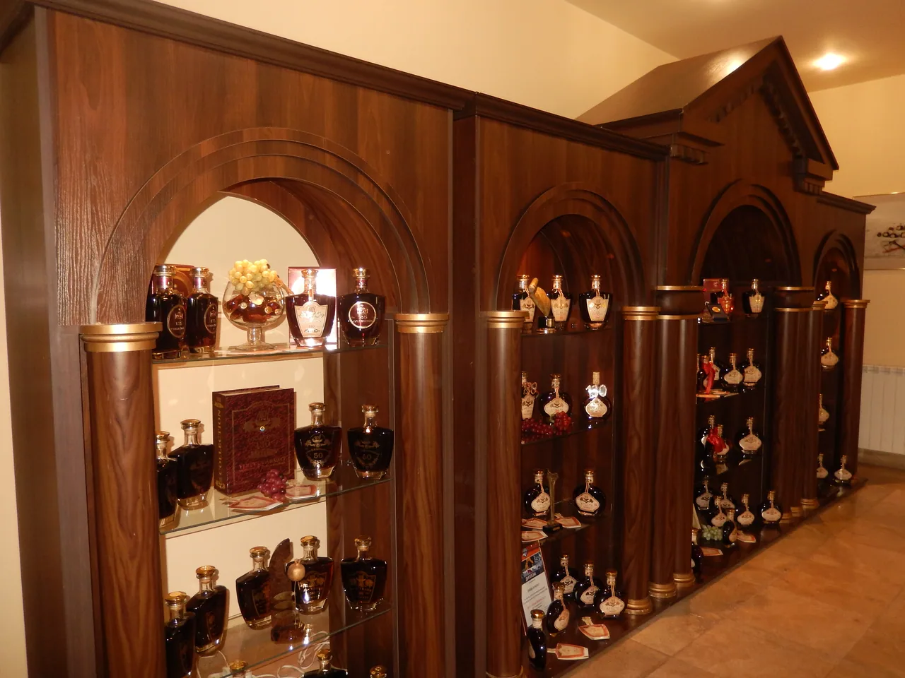 Arched wooden display cabinets filled with decanters of collectible aged brandy at the Noy factory in Yerevan