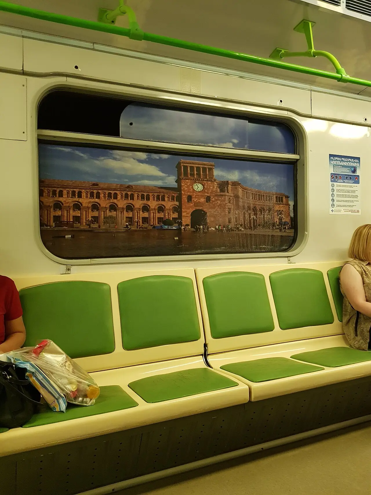 Inside a Yerevan Metro carriage with green seats and a decorative panel of Republic Square where a window would be