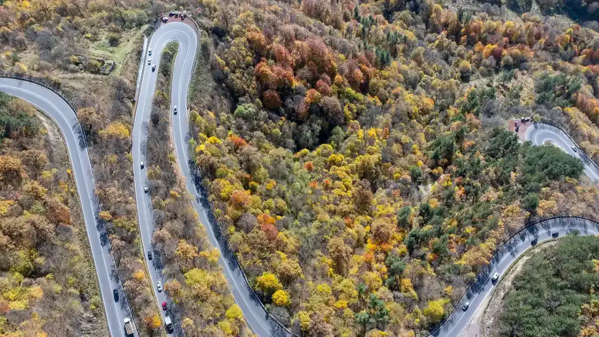 Aerial view of the M4 highway hairpin bends winding through the autumn forest above Dilijan, Armenia