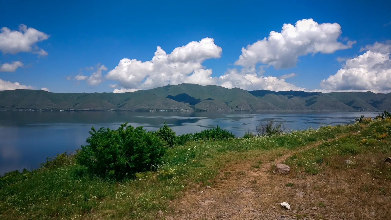 Grassy hills running down to the shoreline of Lake Sevan on a clear day