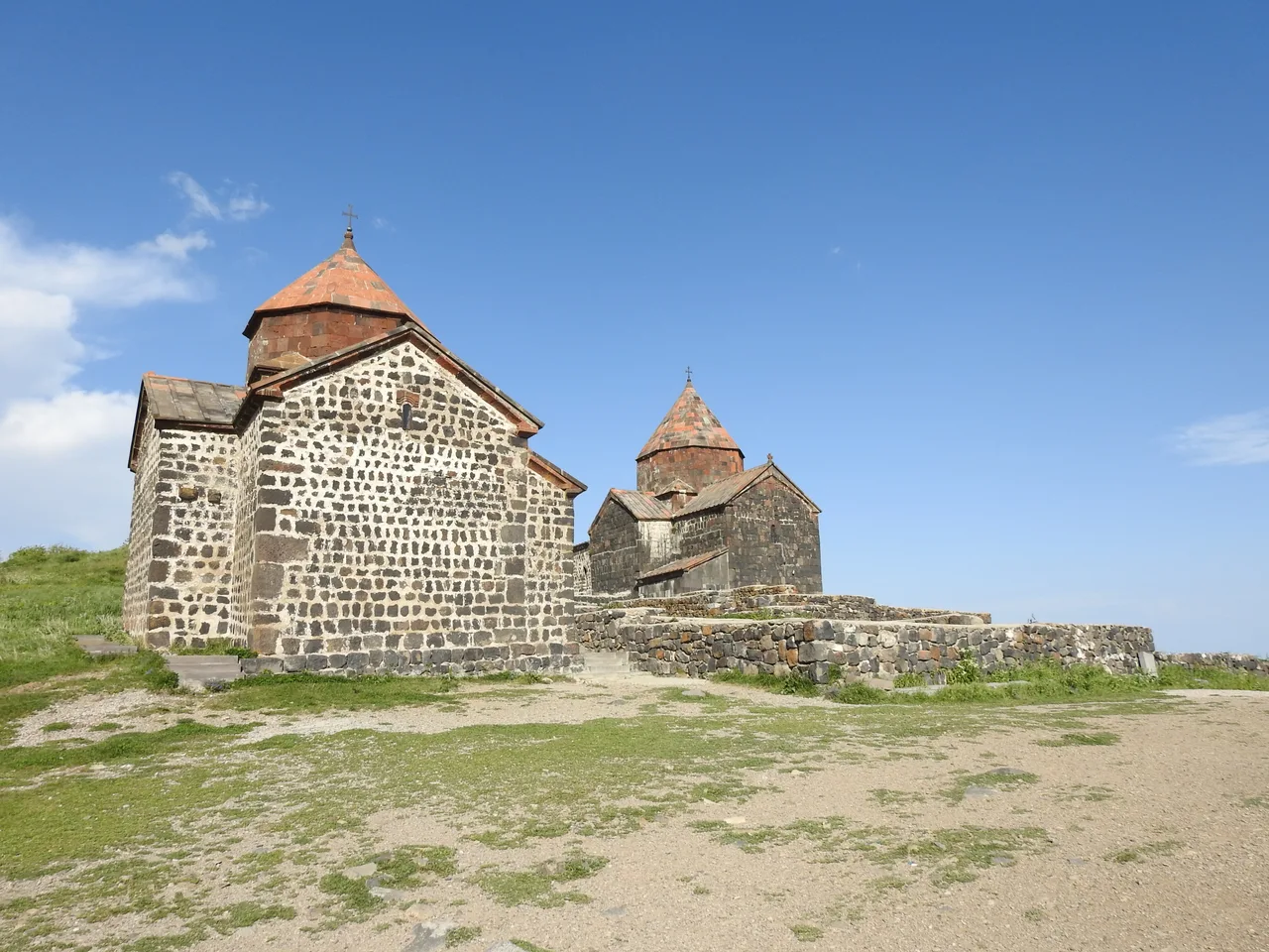 The two dark basalt churches of Sevanavank monastery with their conical domes above Lake Sevan