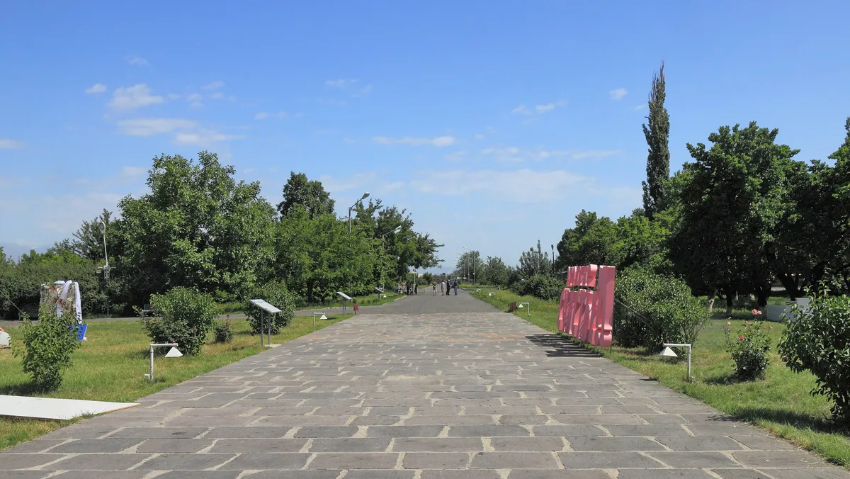 The stone-paved approach path running from the Zvartnots ruins toward the site gate across the open plain