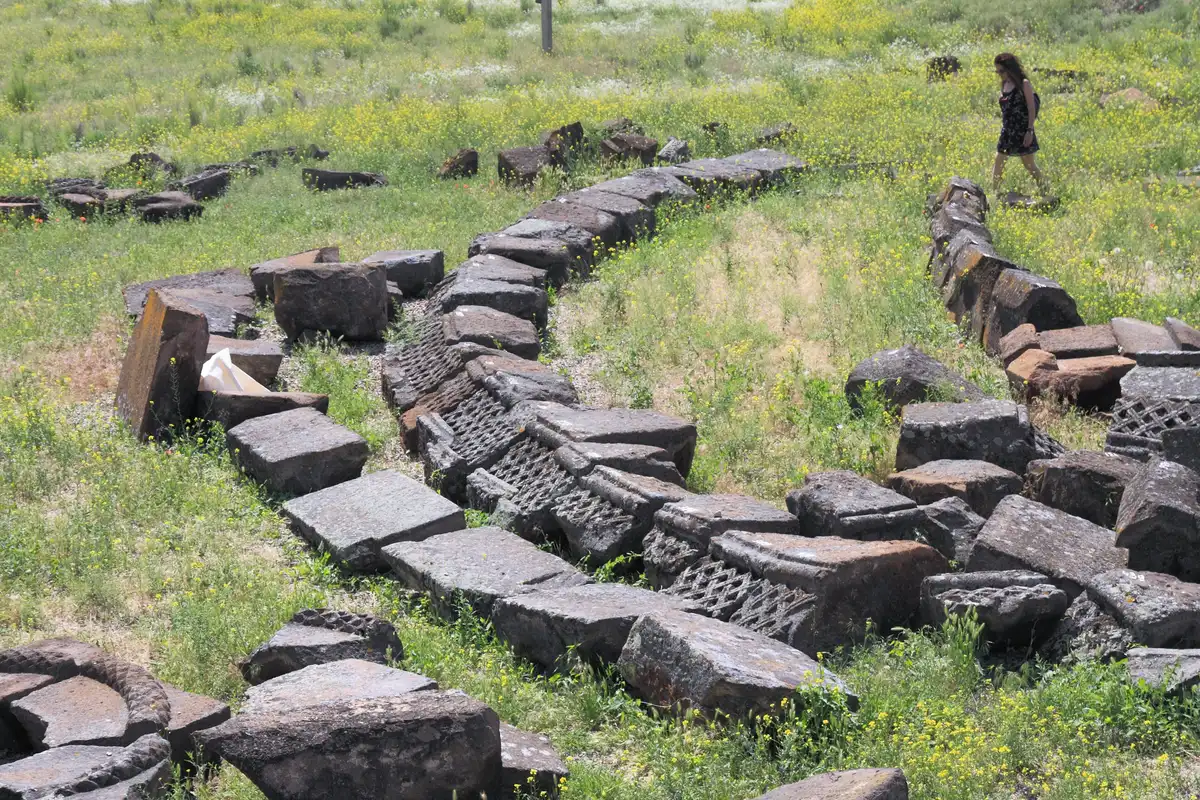 A ring of re-erected round columns from the ground tier of Zvartnots Cathedral standing among the excavated foundations
